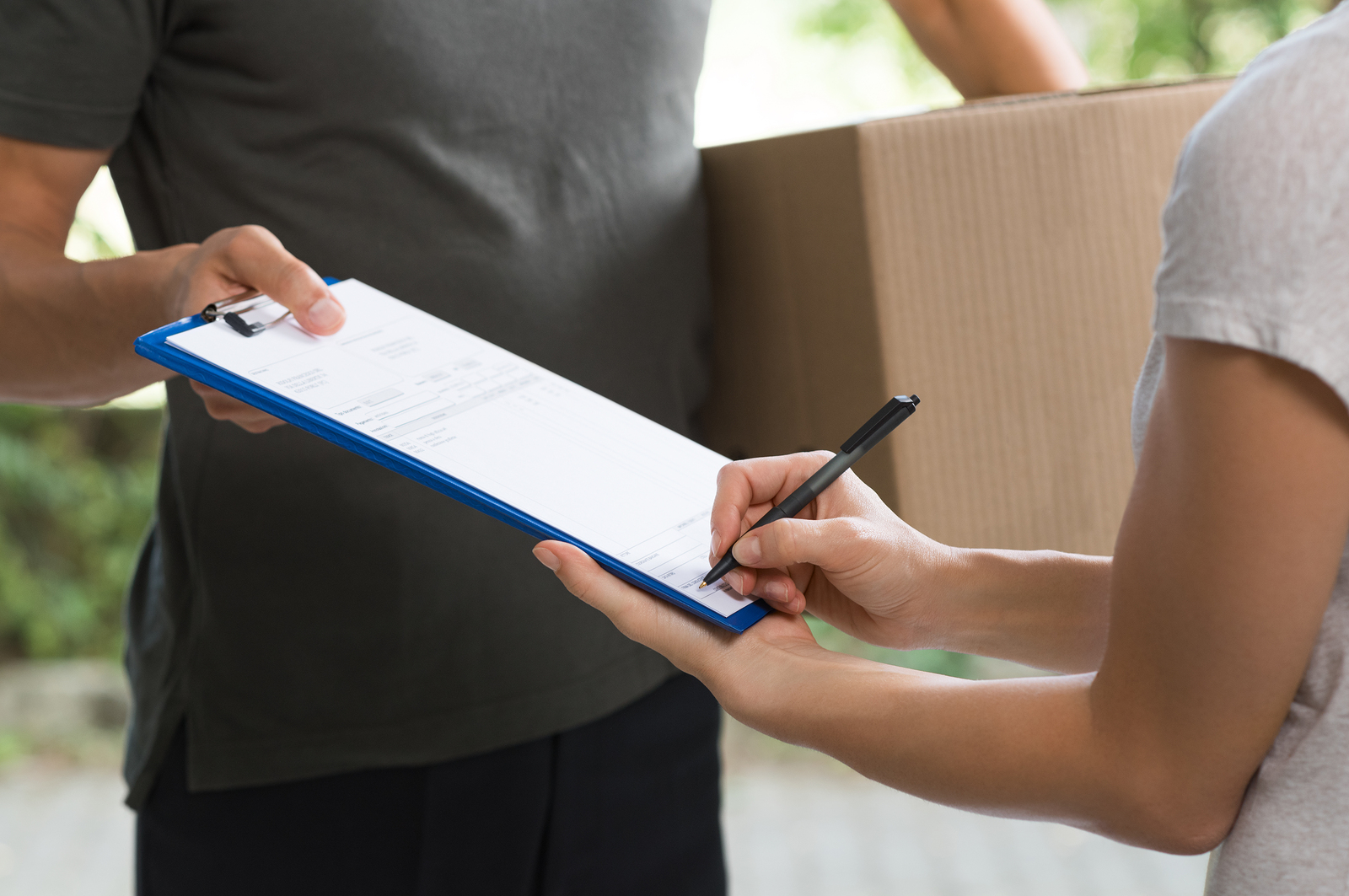 Woman signing receipt of delivery package. Courier man carrying